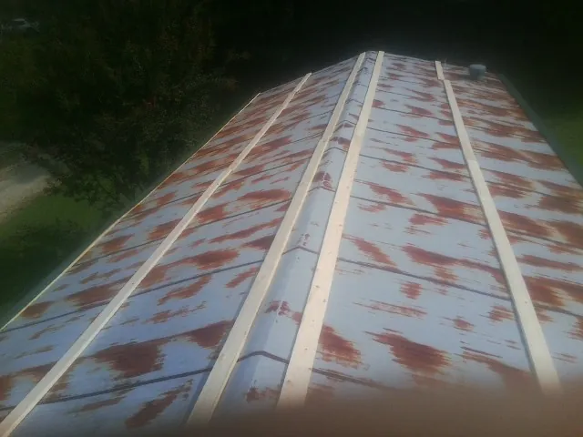 Rusted metal roof panels with new wood purlins before replacement — Storm Damage Roof Repair in Whiteman Air Force Base by Roofing Brothers