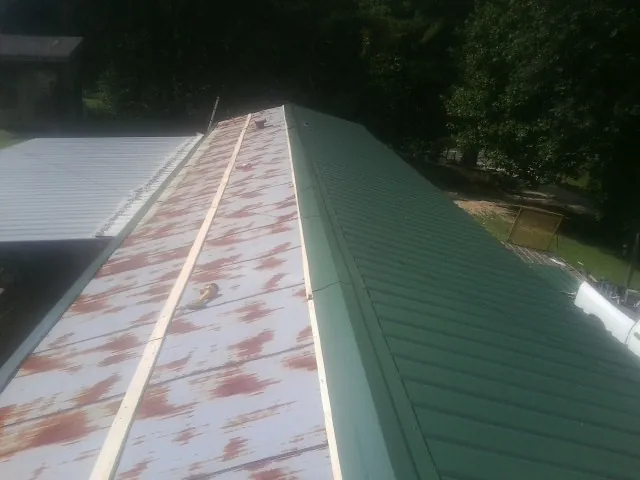 Old rusted panels beside newly installed green metal roofing — Wind Damage Roof Repair by Roofing Brothers in Whiteman Air Force Base