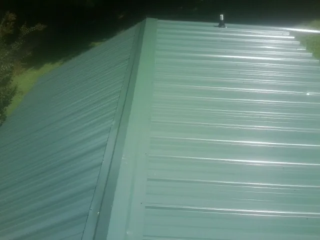 New green metal panels meeting at the ridge of a roof — Flat Roof Repair work by our crew in Whiteman Air Force Base