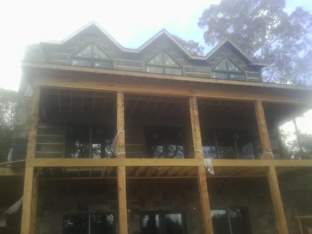 Dormers and porch framing on a large log home under construction — Roof Coating work by our crew in Whiteman Air Force Base