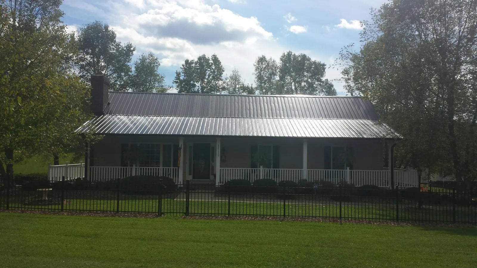 Gray metal roof on a brick ranch with a full width front porch — Gutter Guard Installation work by our crew in Whiteman Air Force Base
