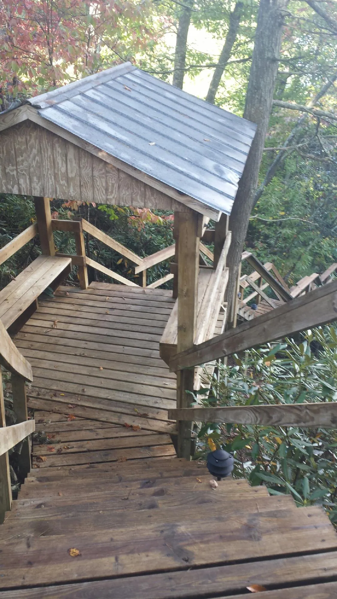 Metal roofed shelter over wooden steps on a wooded walkway — Skylight Repair & Installation work by our crew in Whiteman Air Force Base