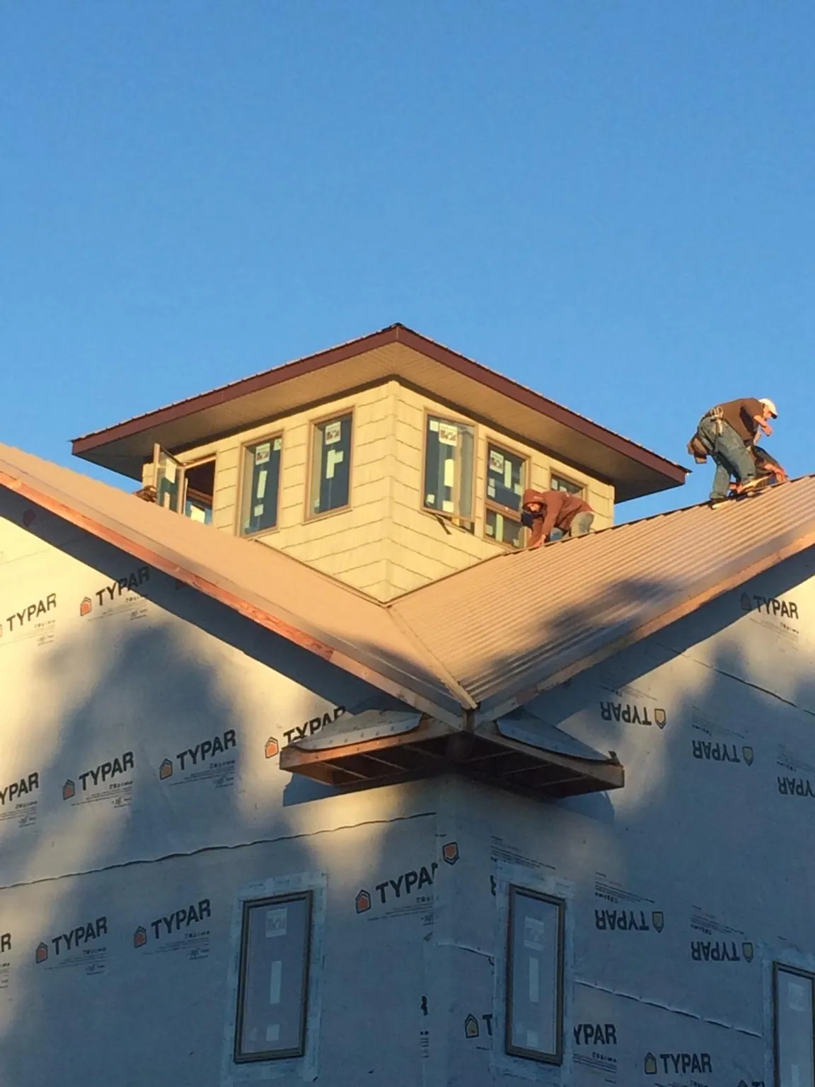 Roofers working around a rooftop cupola on a new metal roof at sunset — Roof Waterproofing in Whiteman Air Force Base by Roofing Brothers